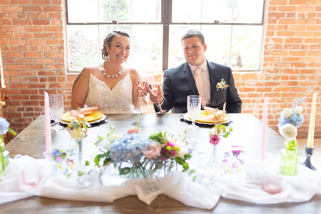 couple with champagne at their sweethear table for the summer bright wedding inspiration