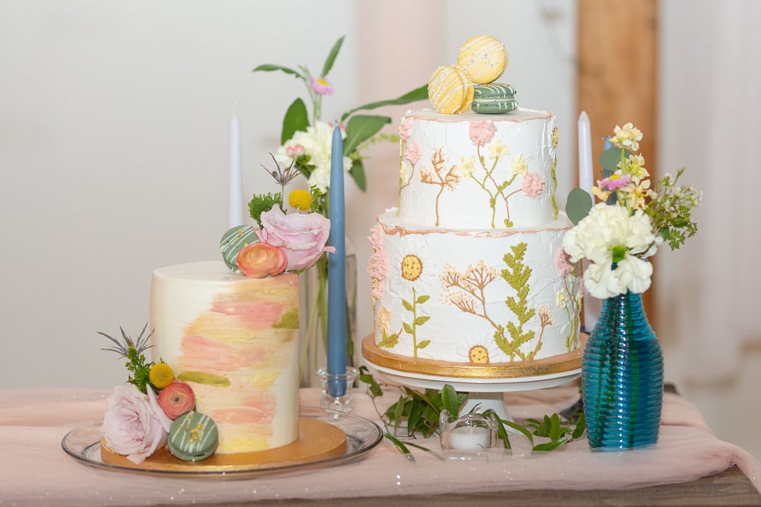 a single-tiered cake and a two-tiered cake with flowers and accents surrounding for summer bright wedding inspiration theme