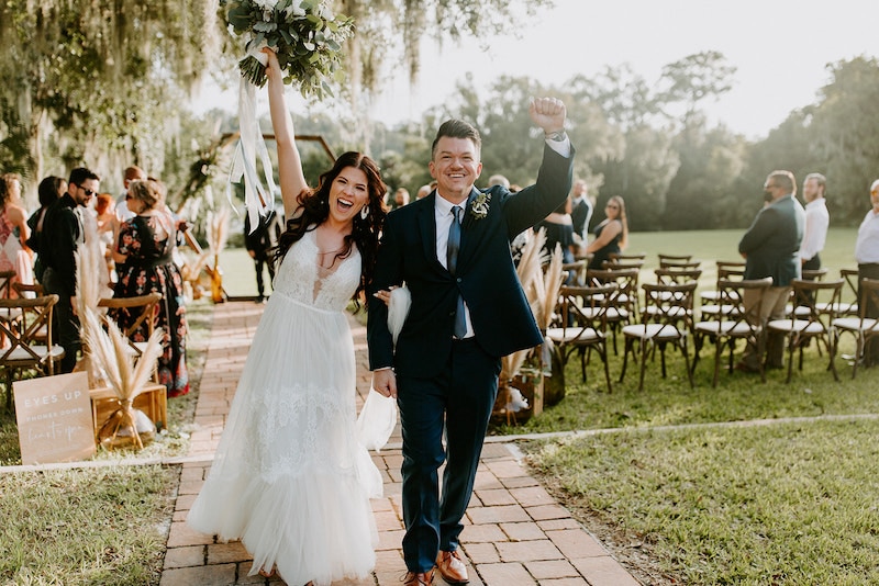 bride and groom celebrating with their hands in the air after their wedding ceremony