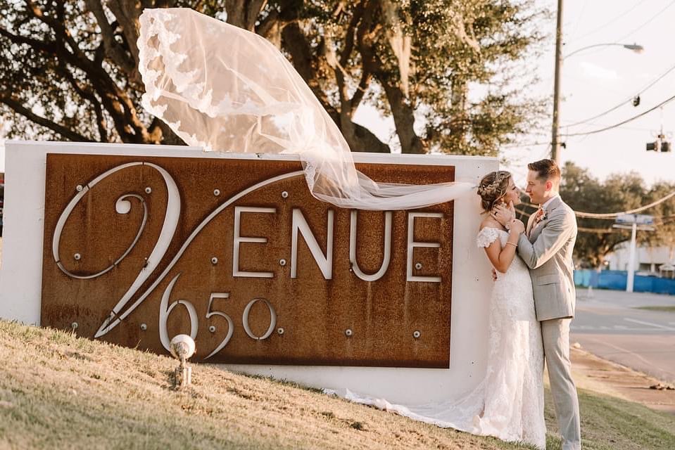 bride and groom with veil over Venue 650 sign