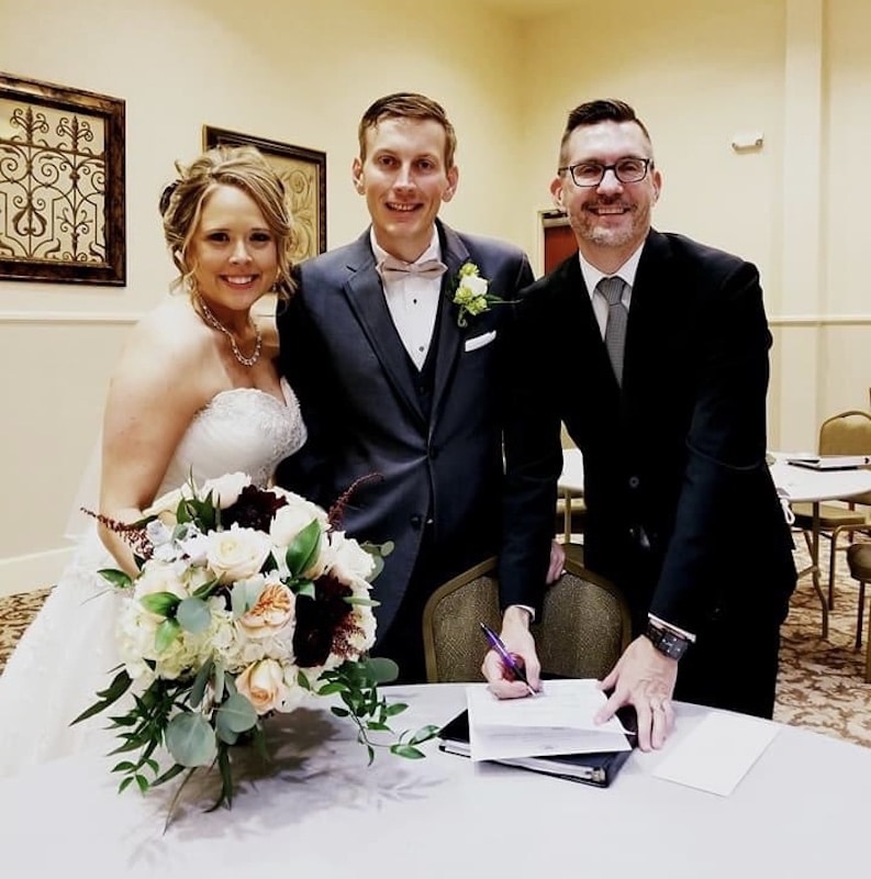 Sam from Weddings By Sam signing marriage certificate with bride and groom