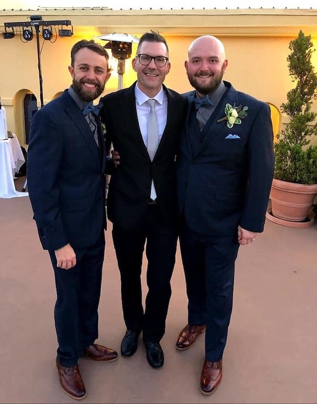 Sam from Weddings By Sam posing with two grooms after wedding ceremony