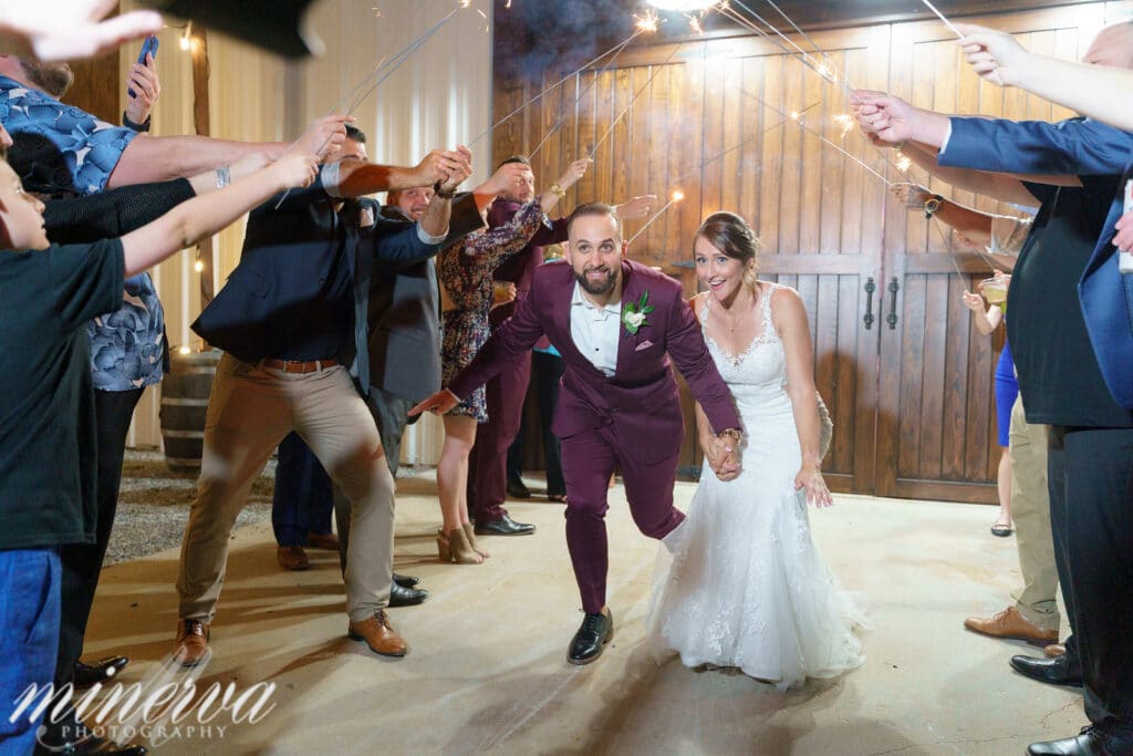 bride and groom ducking and running under sparklers that their guests are holding and waving above them