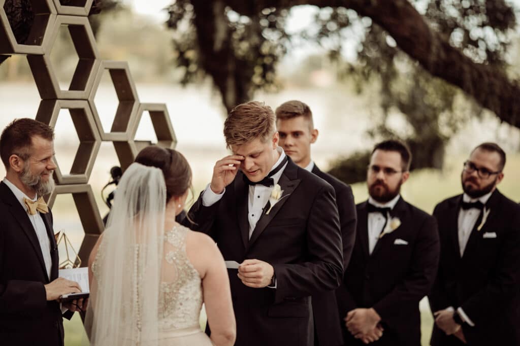 groom wiping away a tear while reading vows during wedding ceremony