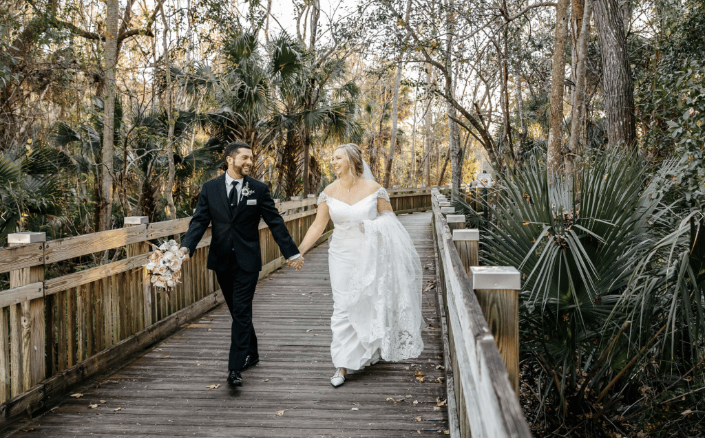 bride and groom walking hand in hand on wooden boardwalk