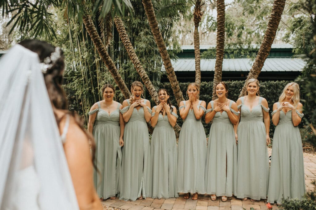 bridesmaids smiling in awe while looking at bride