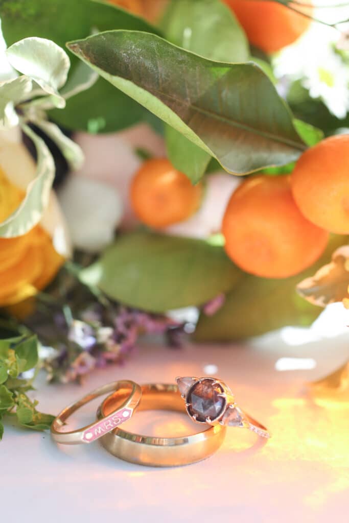 wedding rings next to oranges and flower bouquet