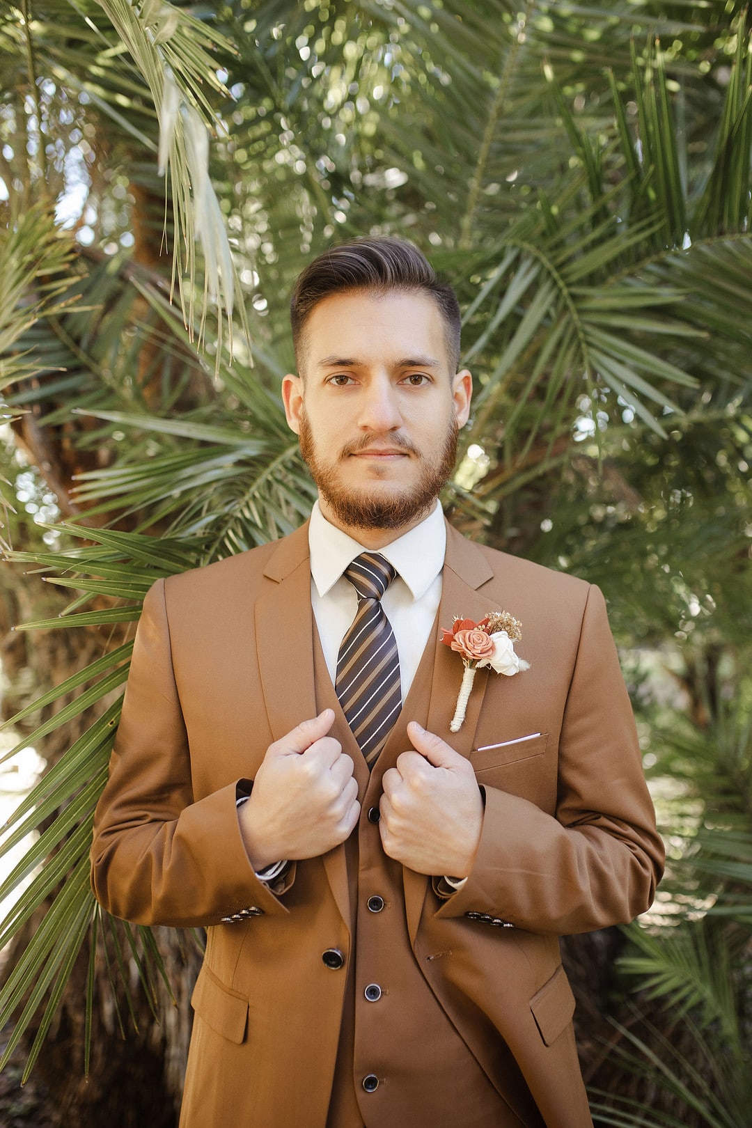 groom looking into the camera while holding the sides of his jacket