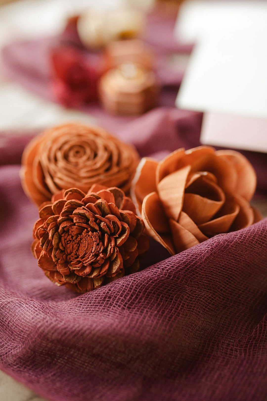 three orange wood flowers on a burgundy cloth for the central florida boho wedding inspiration shoot
