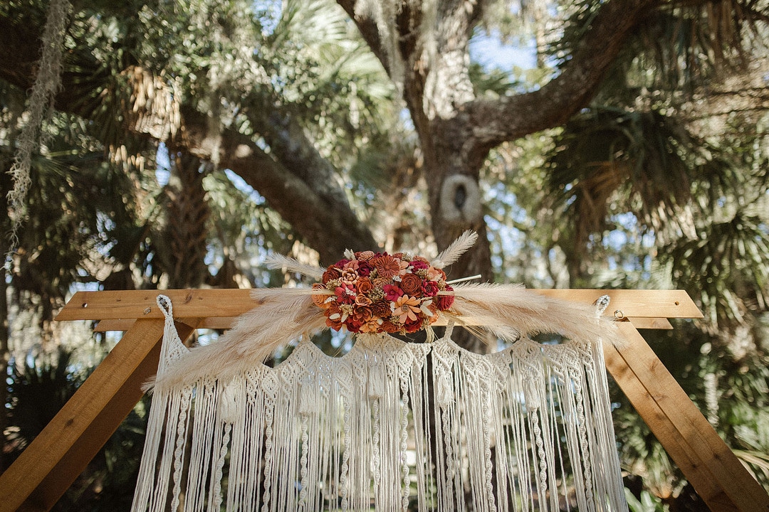 the arbor piece with macreme hanging backdrop and red and yellow florals