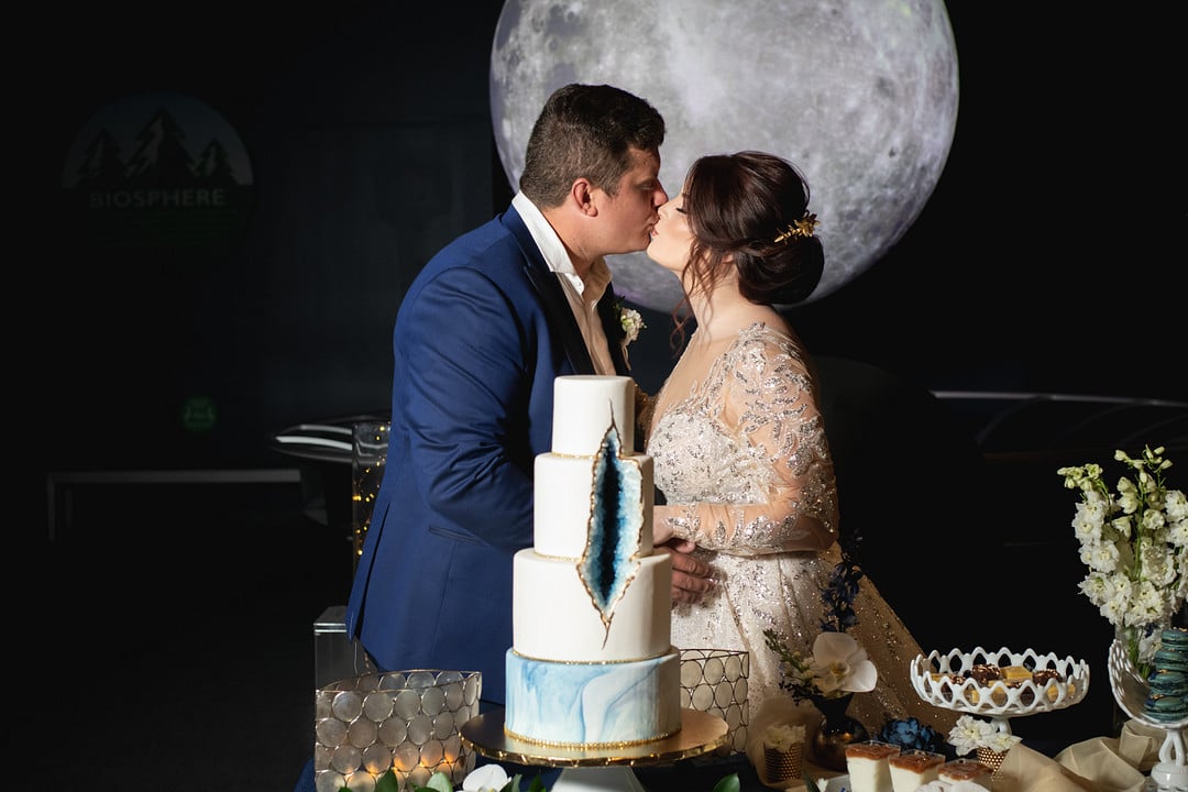 bride and groom kissing behind their blue geode cake table