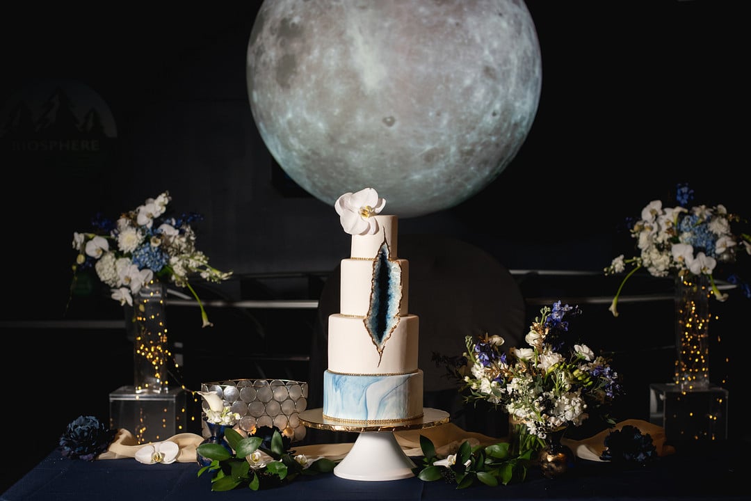 the cake table with blue and white flowers surrounding the geode cake