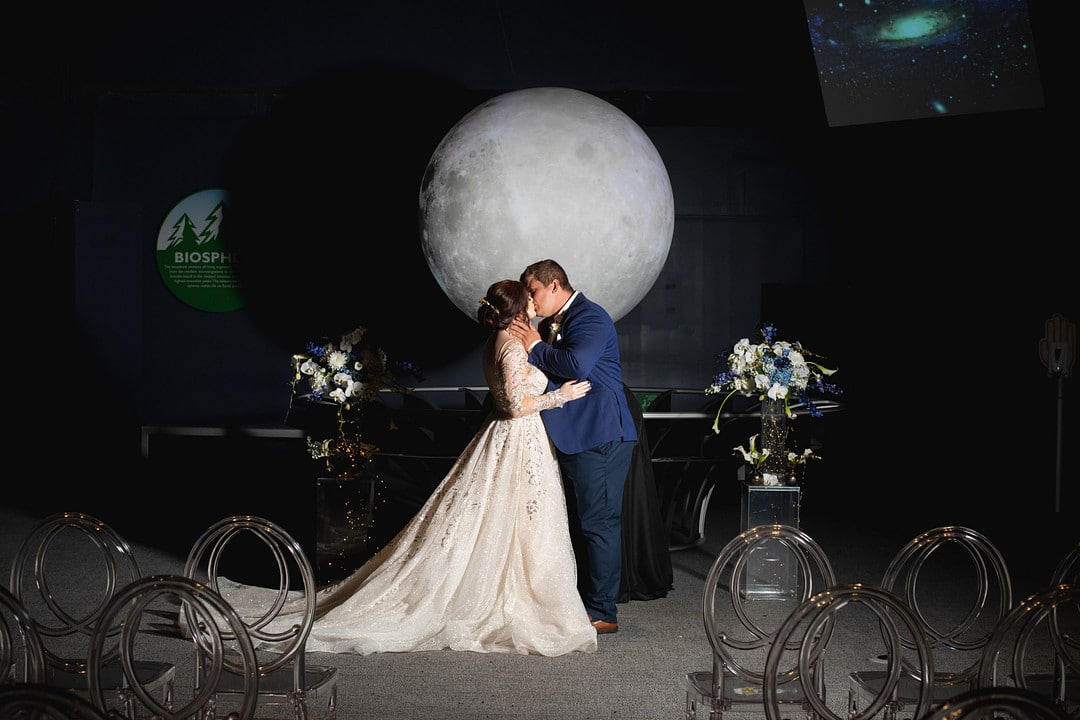 bride and groom kissing with the moon in the background