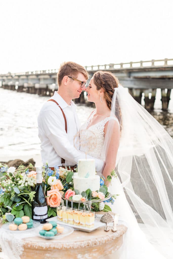 bride and groom holding each other and looking into each others eyes standing next to their cake table