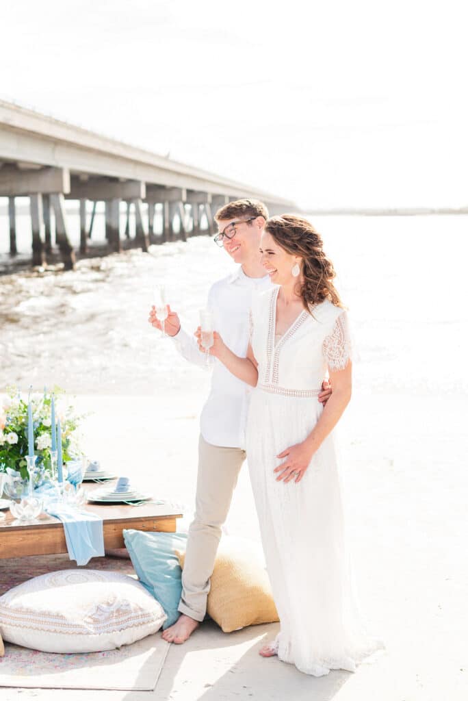 bride and groom holding up their glasses dressed in all white