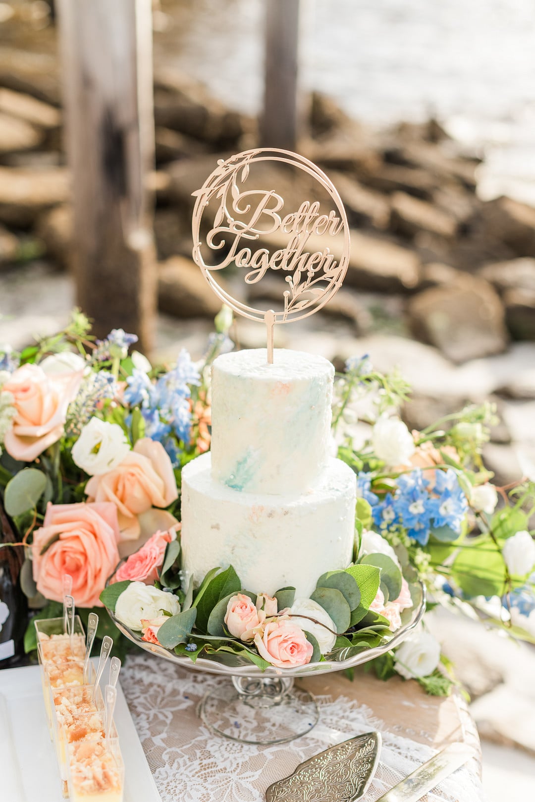 two tier blue and white cakes with florals and greenery surrounding