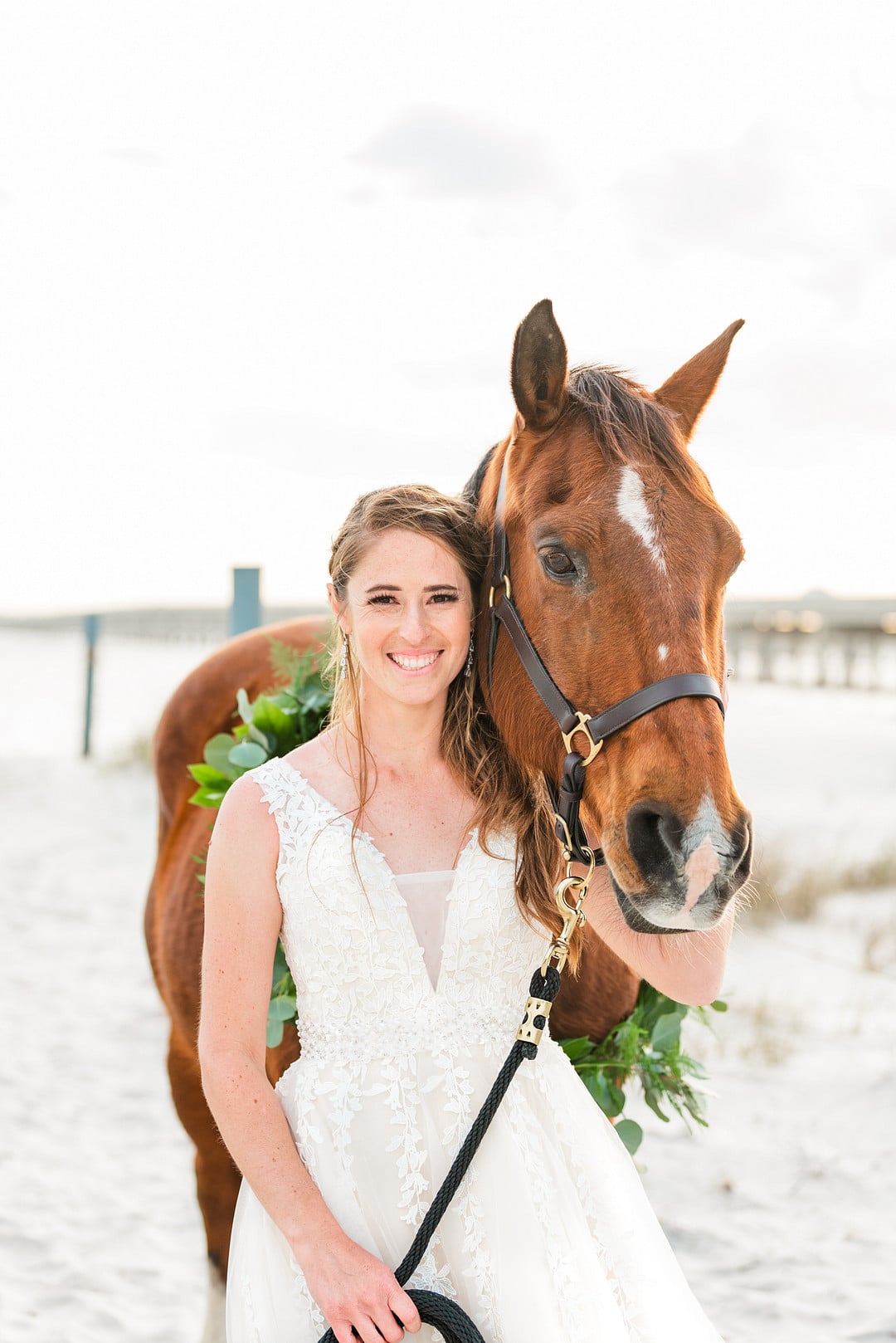bride smiling next to her horse on the beach at amelia island