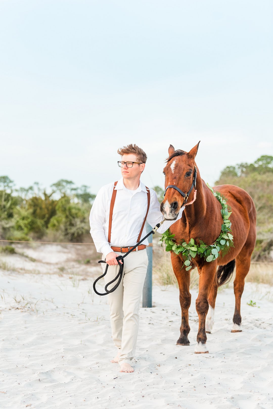the groom walking his brown horse to the beach at amelia island