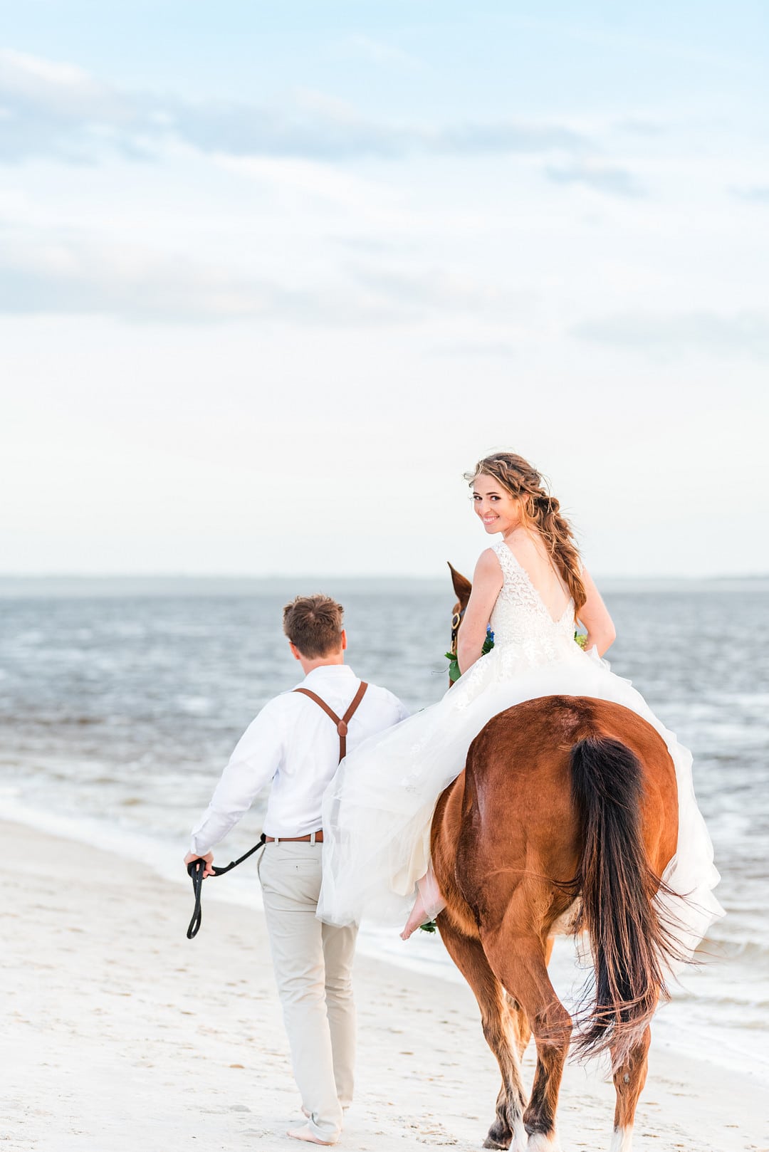 bride riding her horse and looking back while groom walks the horse