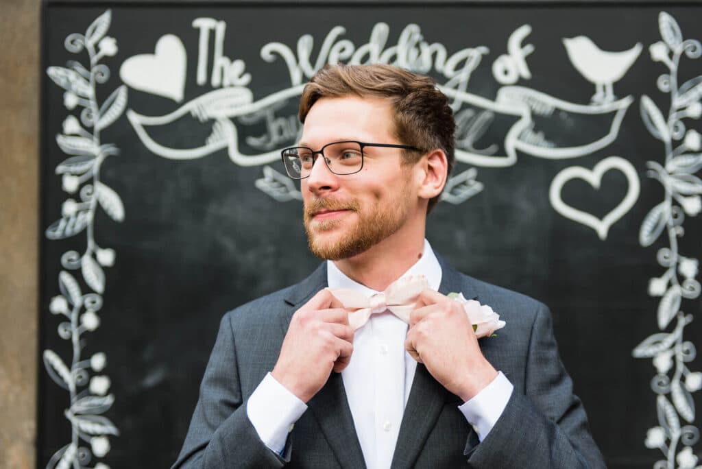 groom adjusting his bow tie on his wedding day