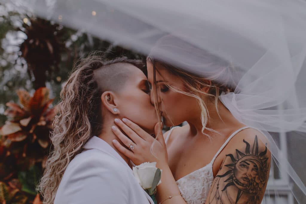 Brides kissing at wedding with sun tattoo