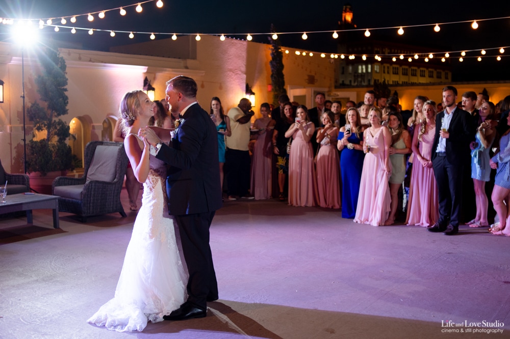 A bride and groom engage in their first dance. It is night time and there are lights over head.
