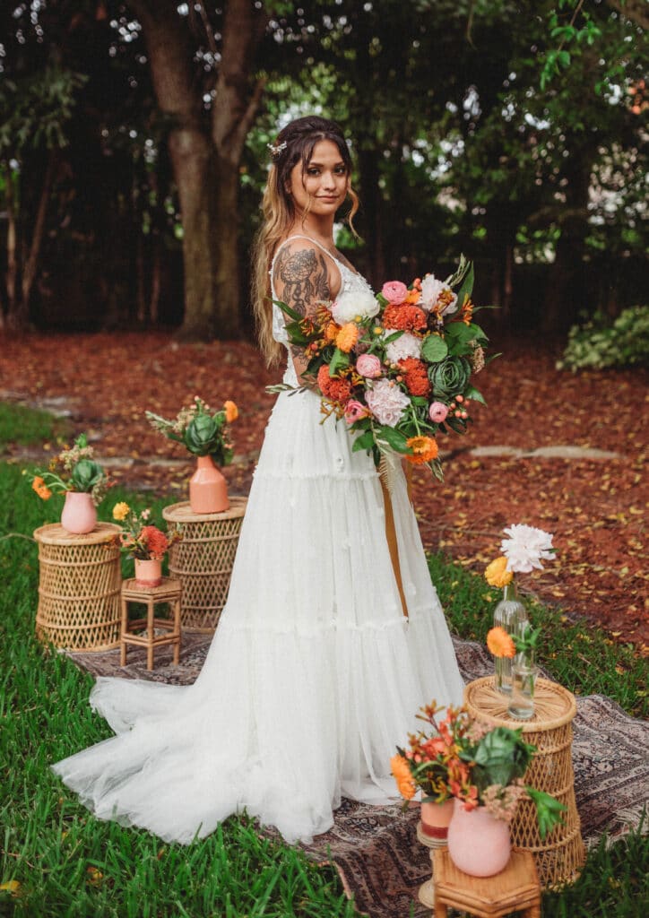 Bride in woodland setting with arm tattoo and fall colored bouquet