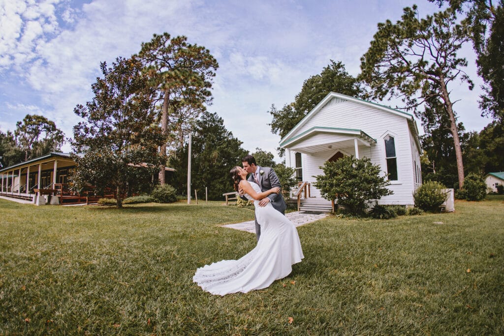 Bride being dipped on lawn of chapel
