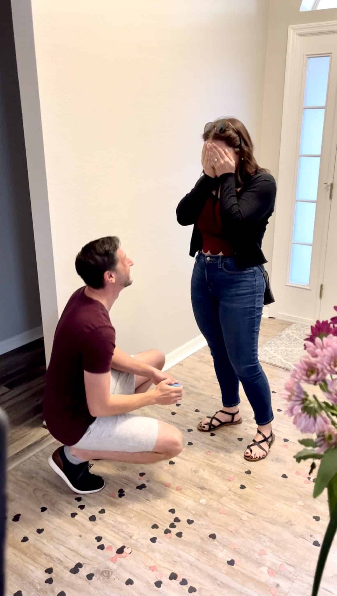 future bride covering her mouth in shock and future groom one one knee proposing during their central florida at home marriage proposal