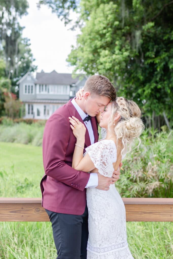 Christmas in July SS 146 - Christmas Themed Wedding Inspiration - Inspiration Shoot Bride and groom embracing outside near a wooden fence.