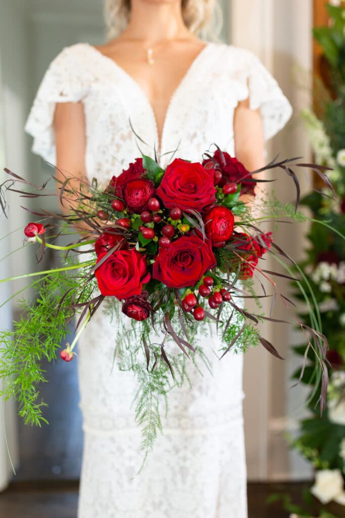 Christmas in July SS 162 1 - Christmas Themed Wedding Inspiration - Inspiration Shoot a close up of the red and green bouquet being held by the bride