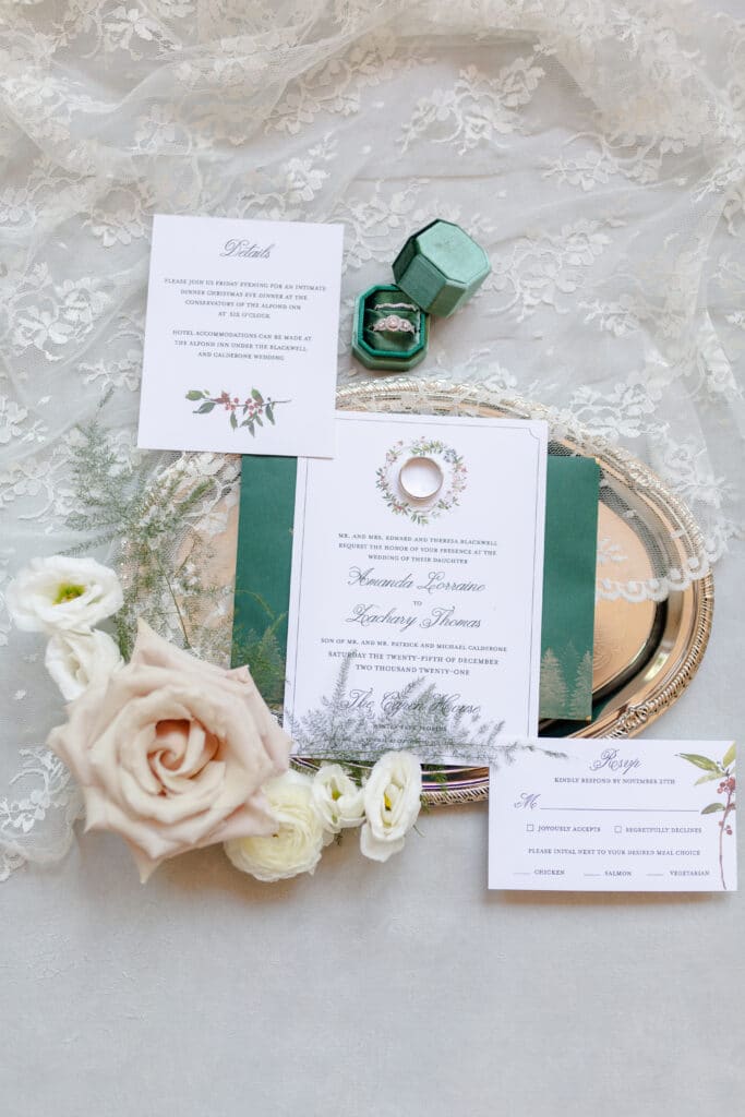 Christmas in July SS 8 - Christmas Themed Wedding Inspiration - Inspiration Shoot Wedding invitation for a Christmas in July themed wedding. The invitation is on a gold platter surrounded by the RSVP card, the bride and groom's rings, and cream flowers.