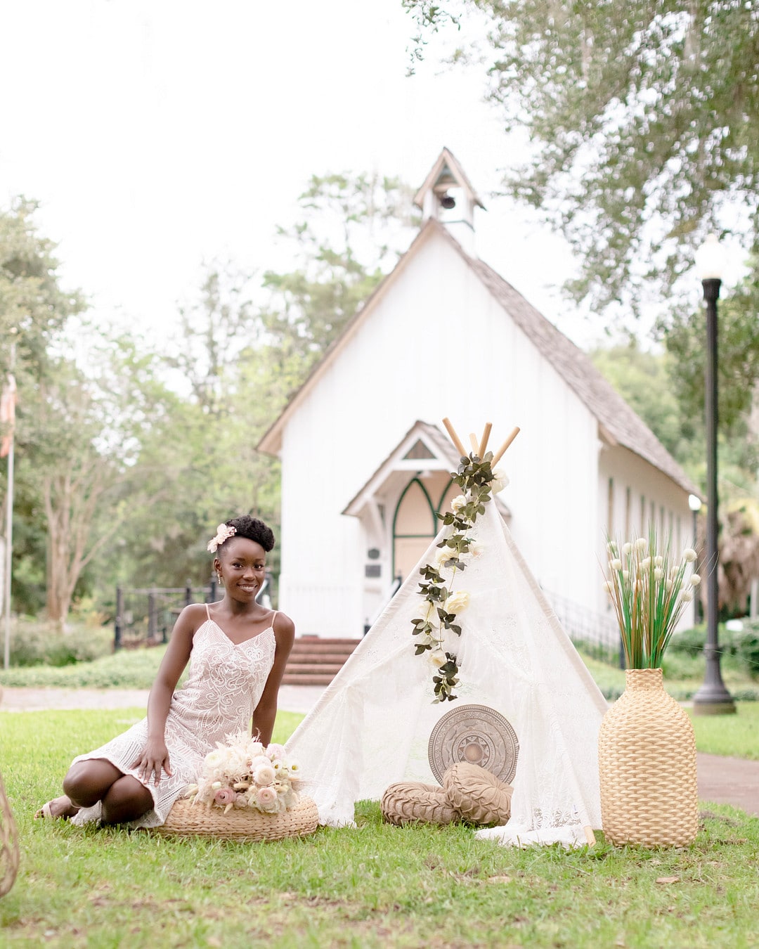 bride sitting next to the white open tent in front of the hall where the picnic wedding inspiration shoot was held.