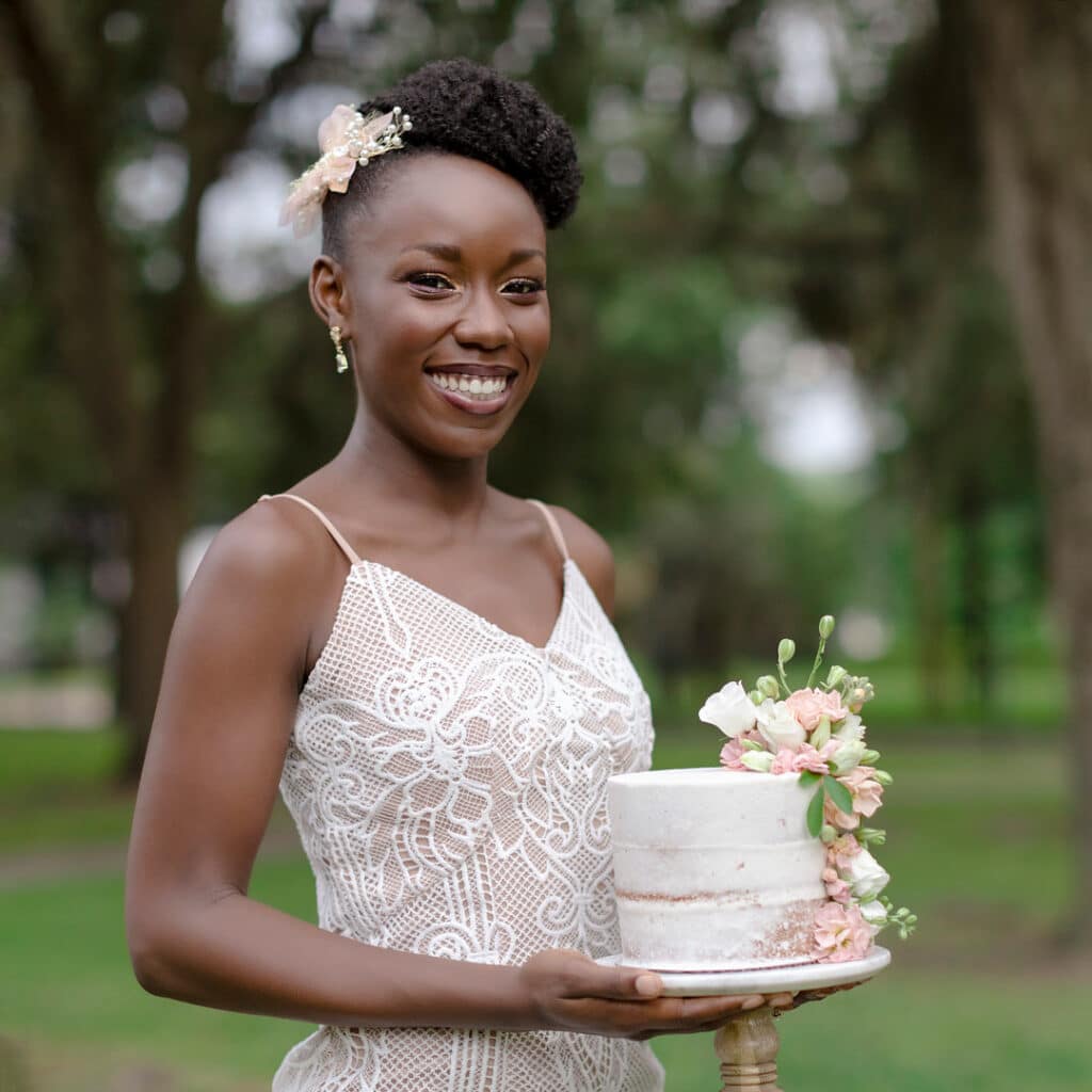 the bride smiling and holding the wedding cake for the picnic wedding inspiration shoot.