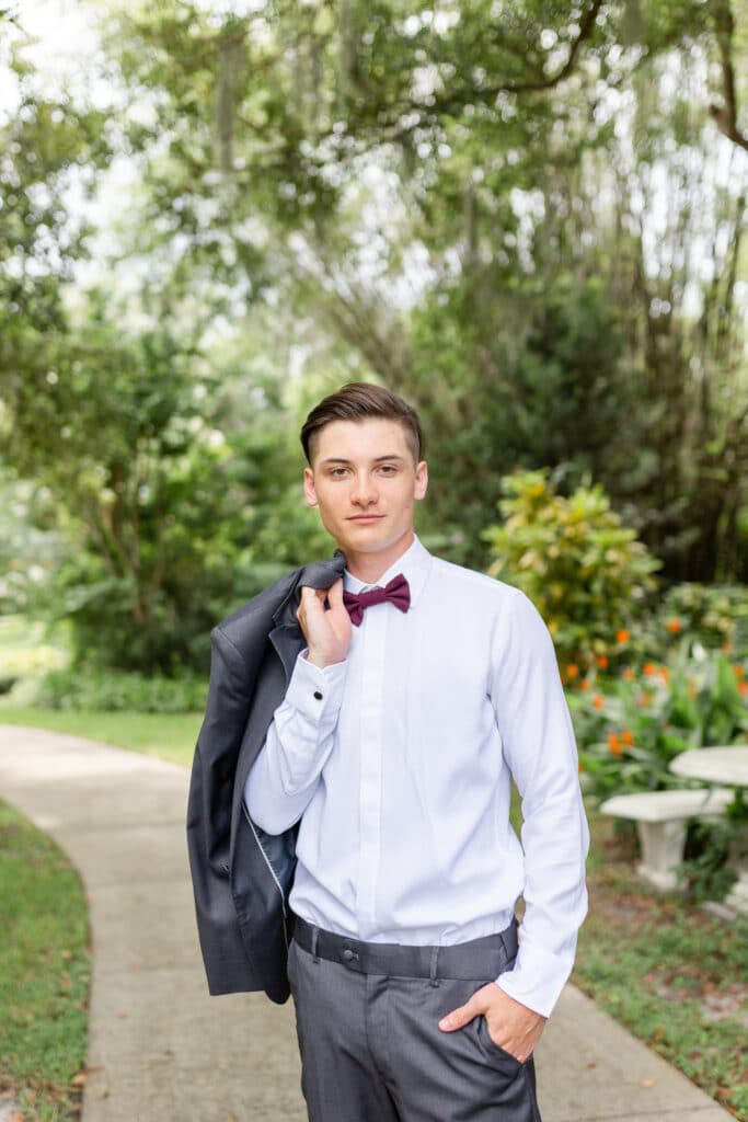 Sneak Peak 12 - Christmas Themed Wedding Inspiration - Inspiration Shoot groom holding his jacket behind his shoulder and posing