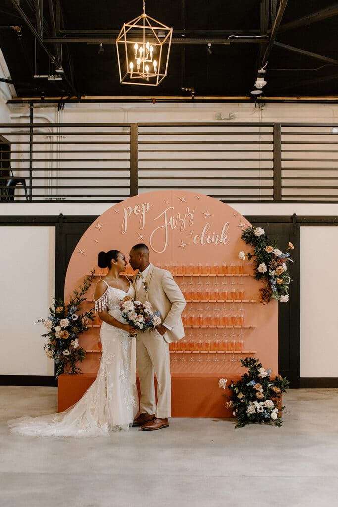 Summer Urban Loft Wedding Inspiration Grace Jicha Venue At The Block Wedding BrideandGroom 38 websize low - Urban Loft Wedding Inspiration - Styled Shoot bride and groom standing in front of the pink champagne wall.