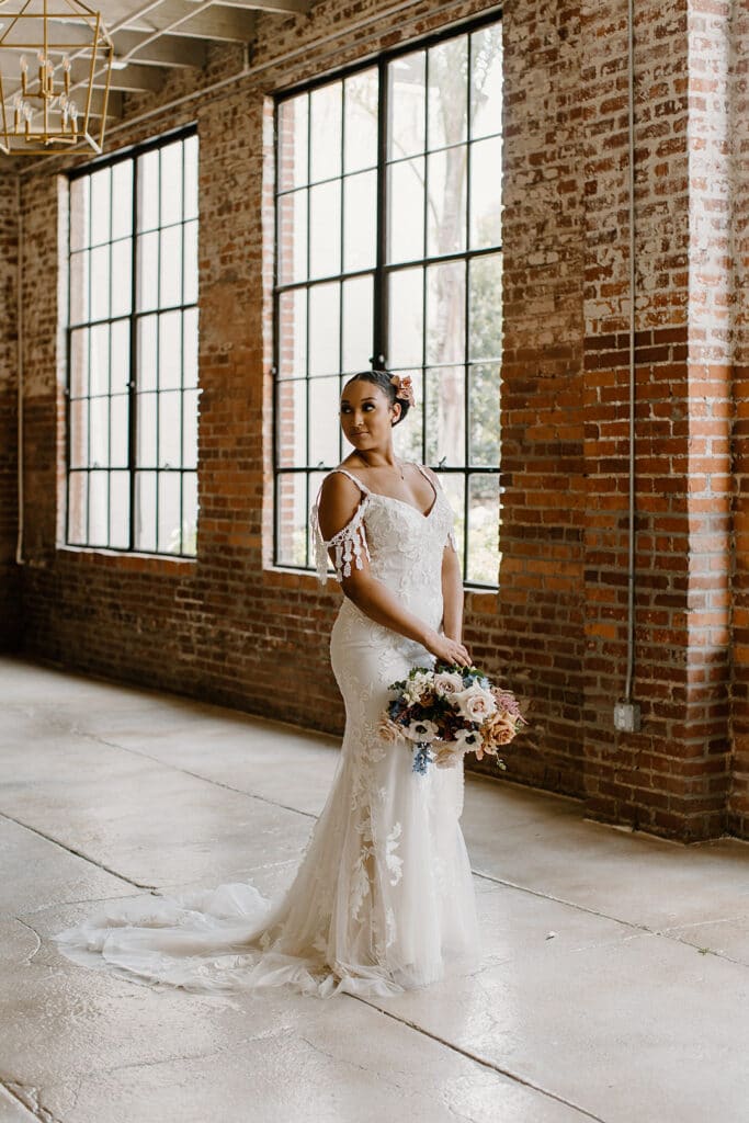 Summer Urban Loft Wedding Inspiration Grace Jicha Venue At The Block Wedding BrideandGroom 55 websize low - Urban Loft Wedding Inspiration - Styled Shoot bride to be standing in her wedding dress and holding her bouquet.
