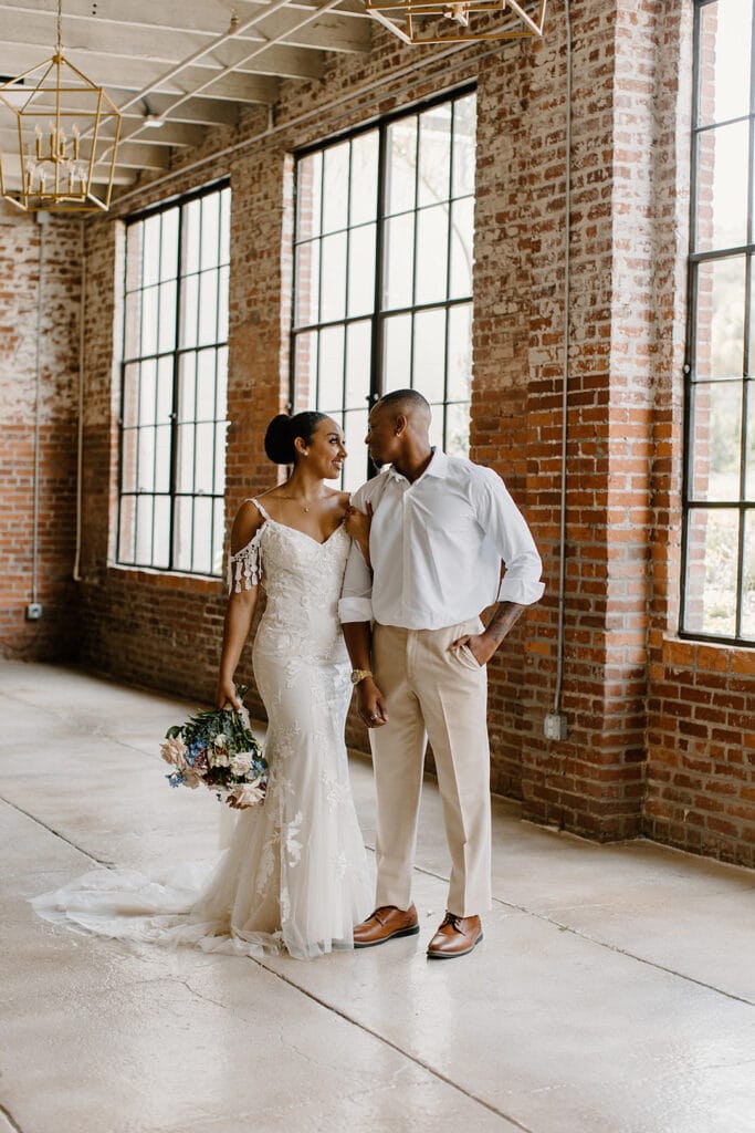Summer Urban Loft Wedding Inspiration Grace Jicha Venue At The Block Wedding BrideandGroom 57 websize low - Urban Loft Wedding Inspiration - Styled Shoot full shot picture of the bride and groom looking at each other in a large brick room