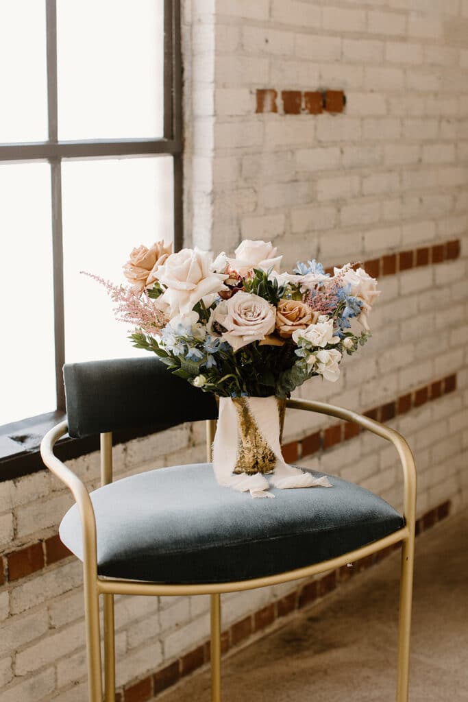 Summer Urban Loft Wedding Inspiration Grace Jicha Venue At The Block Wedding Floral 2 websize low - Urban Loft Wedding Inspiration - Styled Shoot the bride's bouquet sitting on a blue and gold chair for the urban loft wedding inspiration shoot.