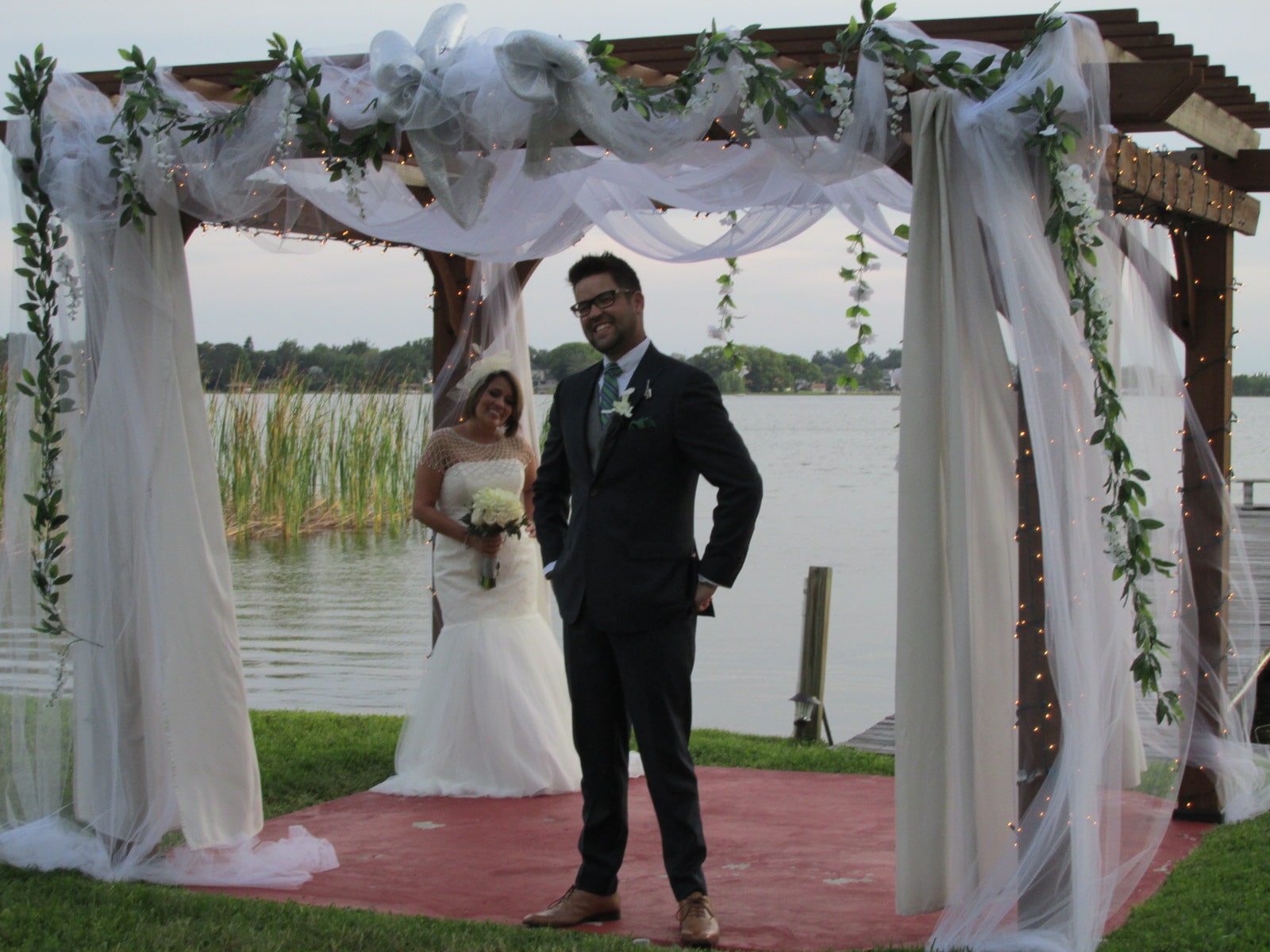 bride & groom under covered gazebo by water