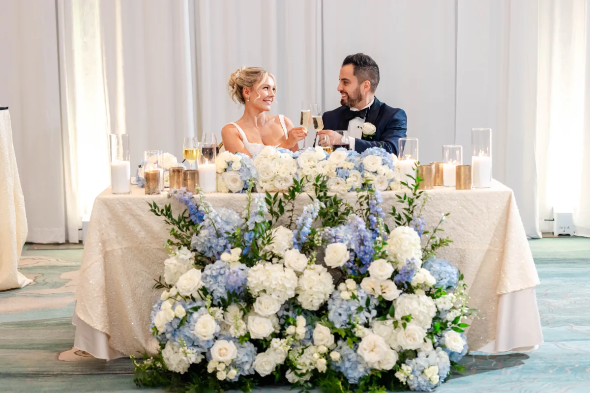 Newlywed couple sharing a toast at their sweetheart table during a Waldorf Astoria Orlando wedding reception.