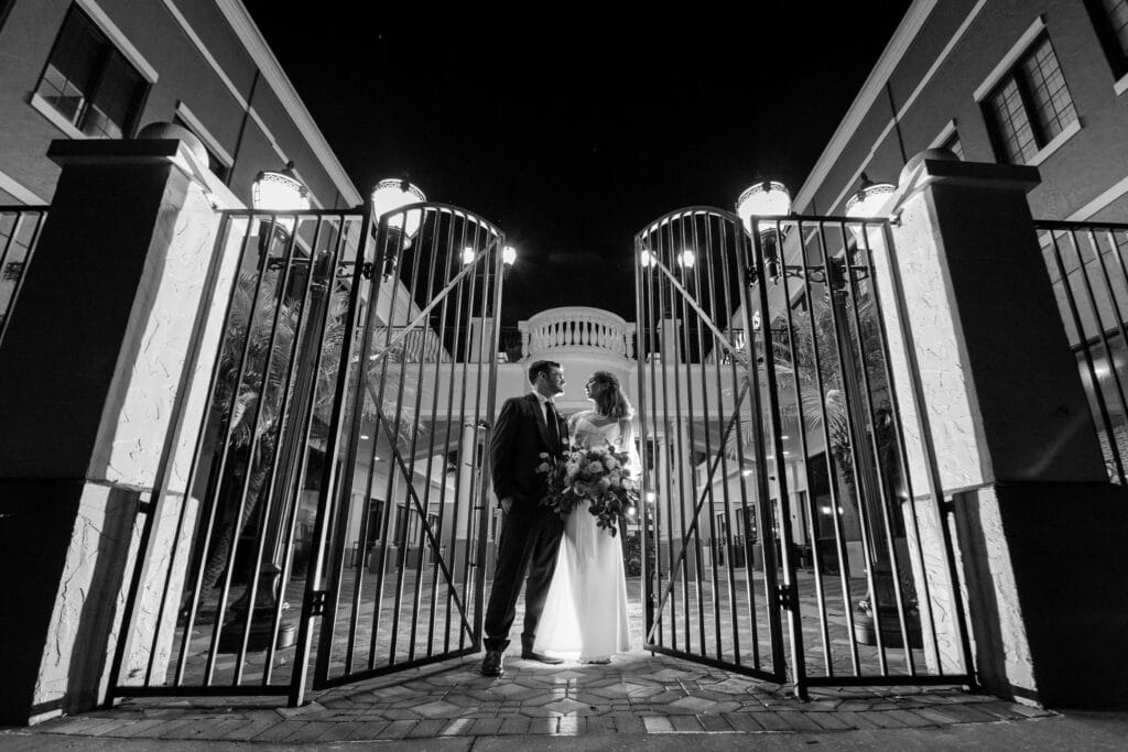 bride and groom against gate in black and white photo by Steven Miller Photography
