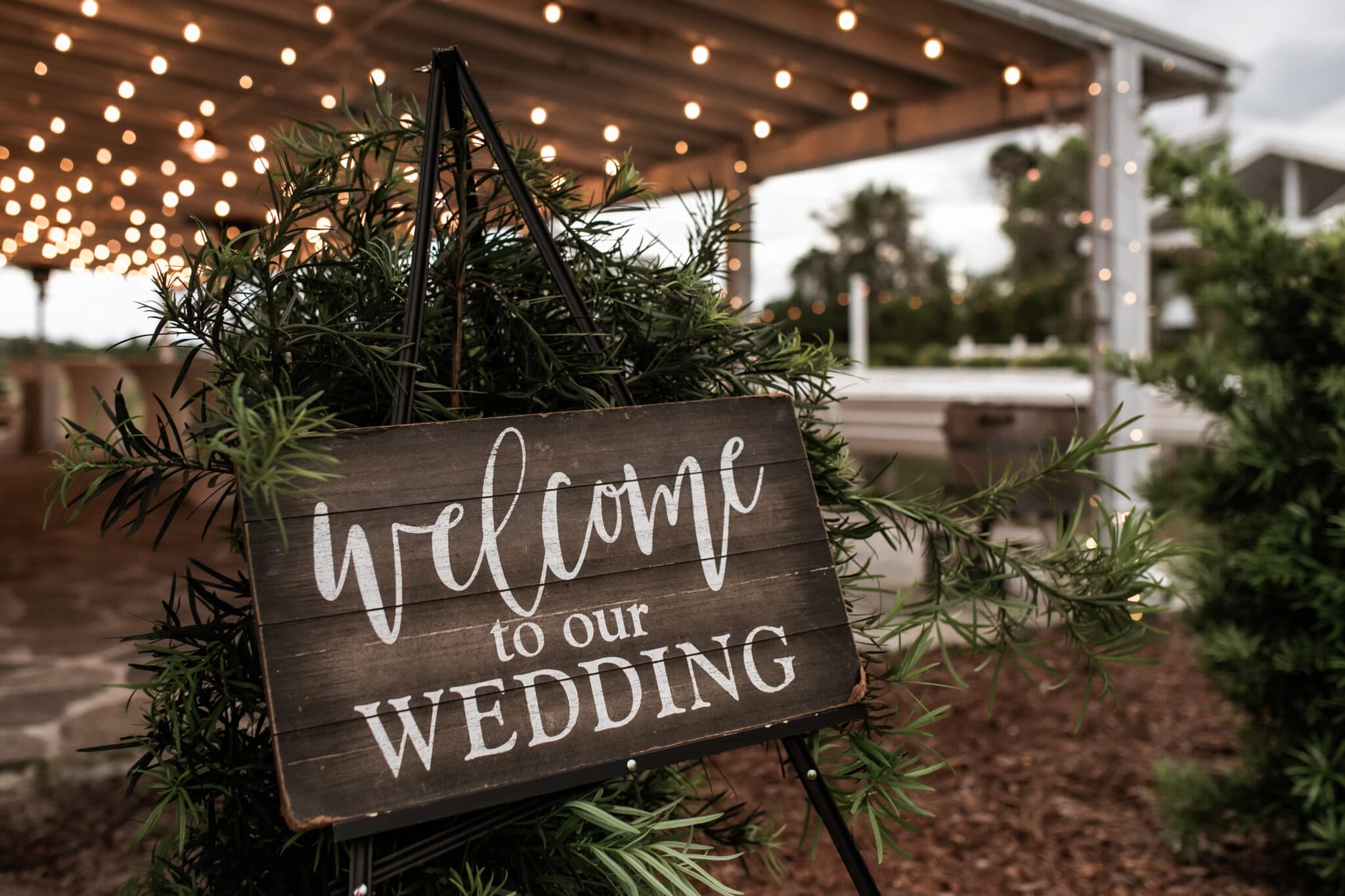 the welcome sign for the barn wedding with greenery and rustic feeling.
