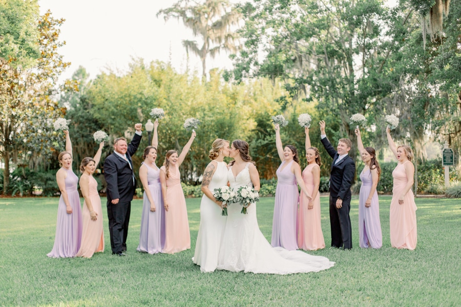 Brides kissing with wedding party cheering