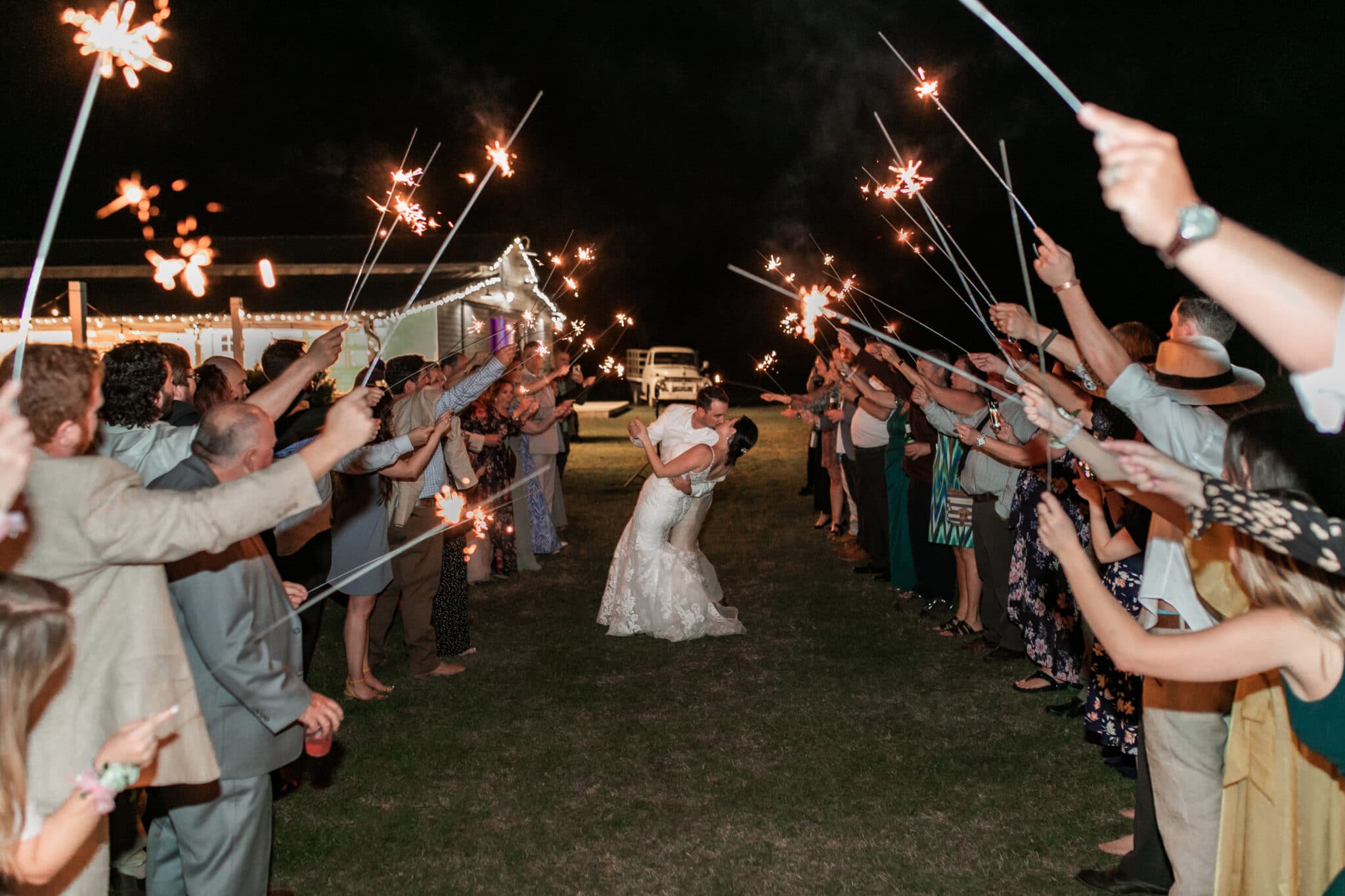 bride and groom kissing as they exit their wedding with their attendees holding sparklers around them