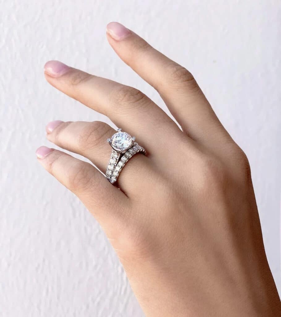 Woman's hand with engagement and wedding ring in diamonds