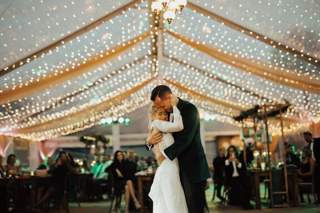 Bride and groom embracing under twinkle lights