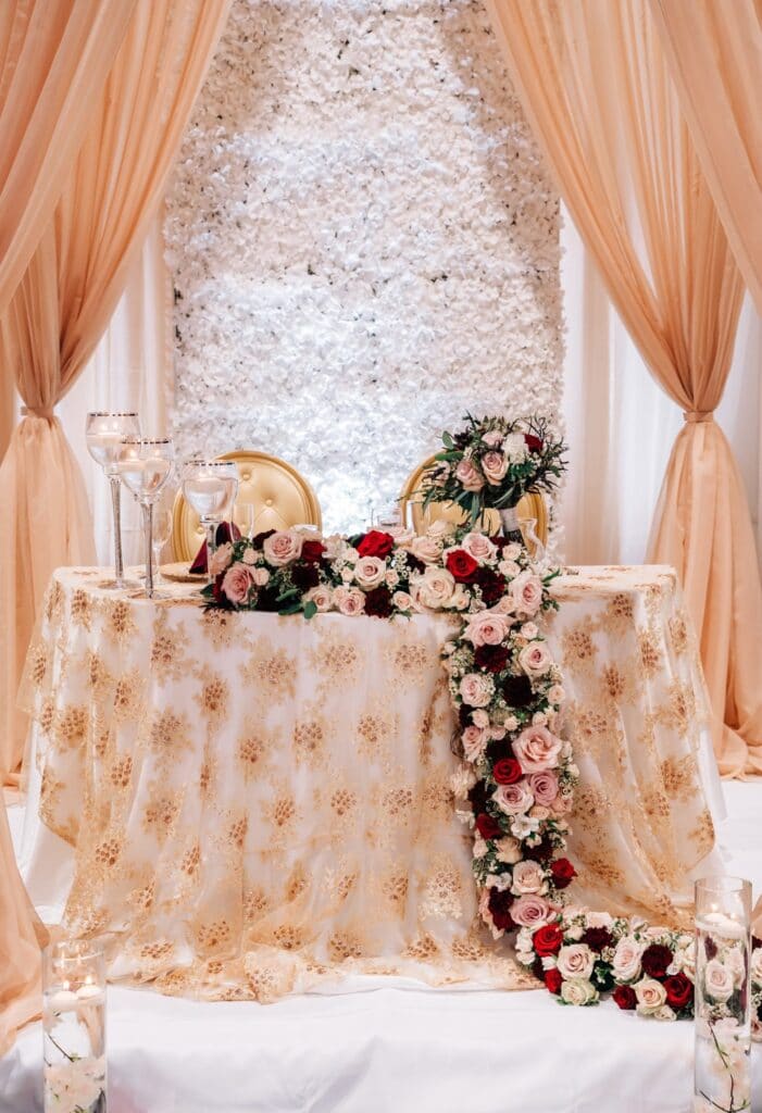 Bride and groom table with peach colored tablecloth and cascading flowers
