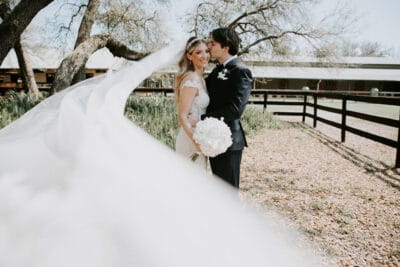 Groom kissing his bride. She is holding a pure white bouquet of flowers