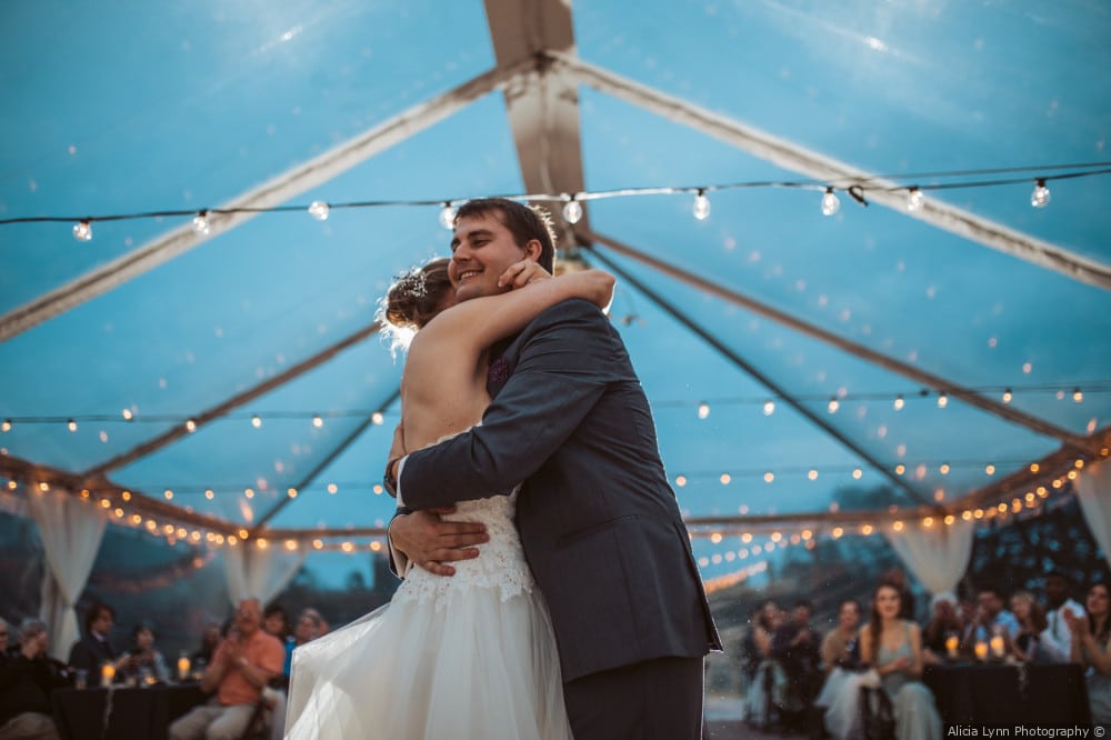 Bride and groom hugging undera tent with string lights